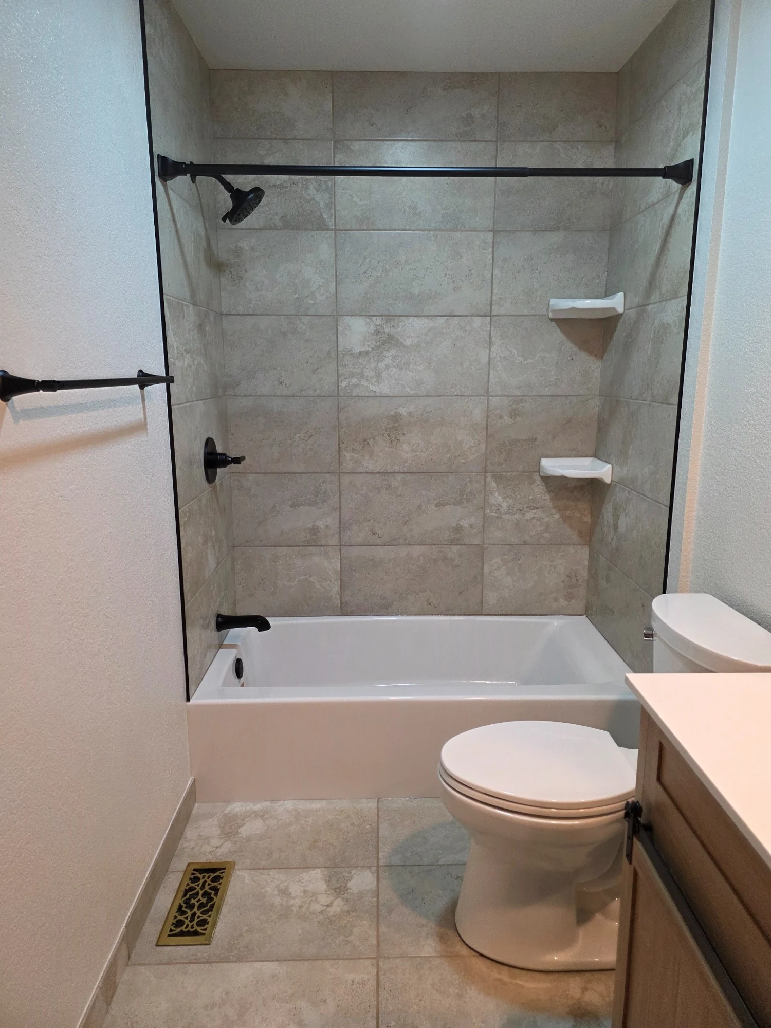 Tiled bathtub surround with dark shower fixtures