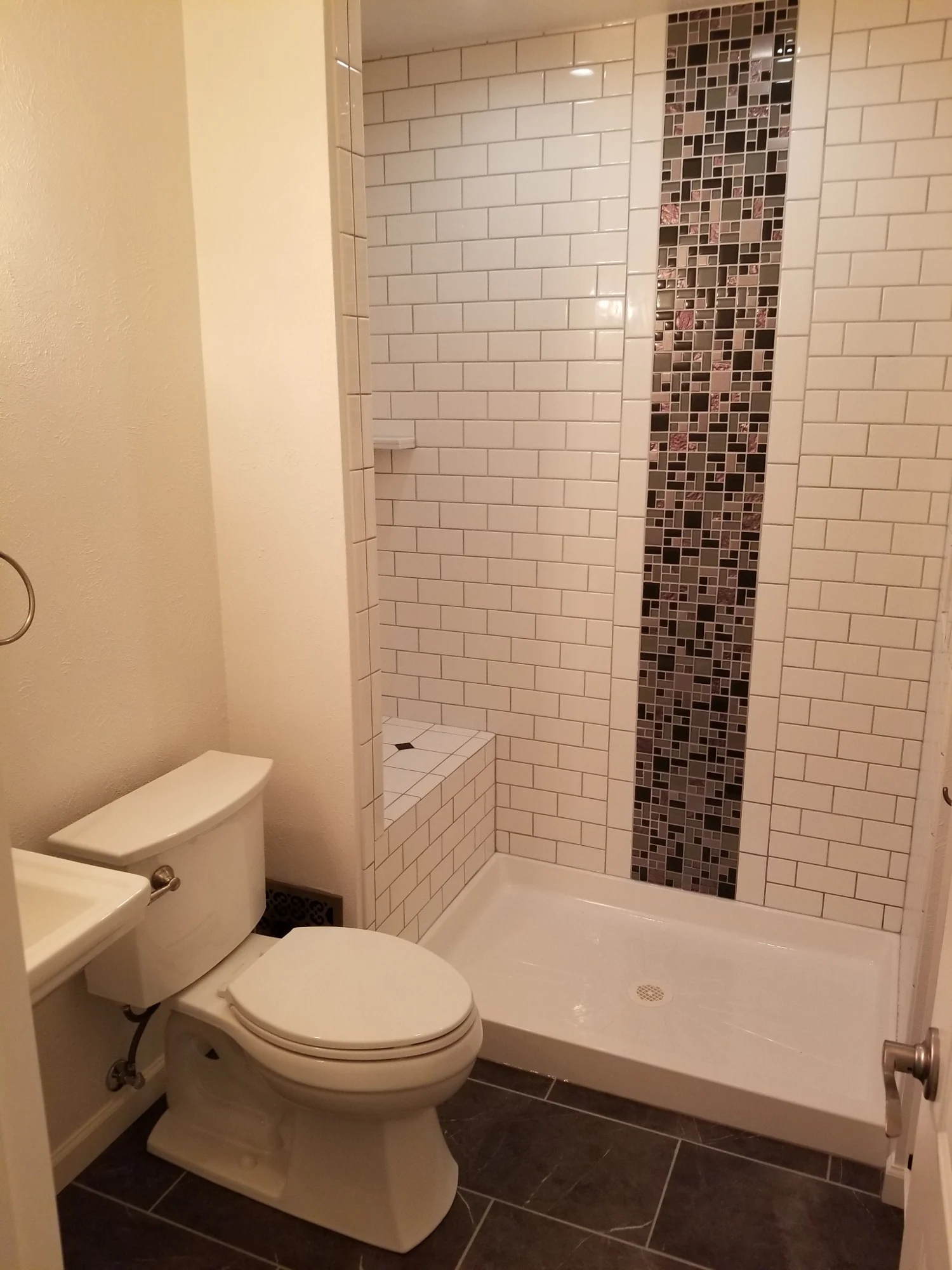 White subway tile shower with vertical mosaic accent
