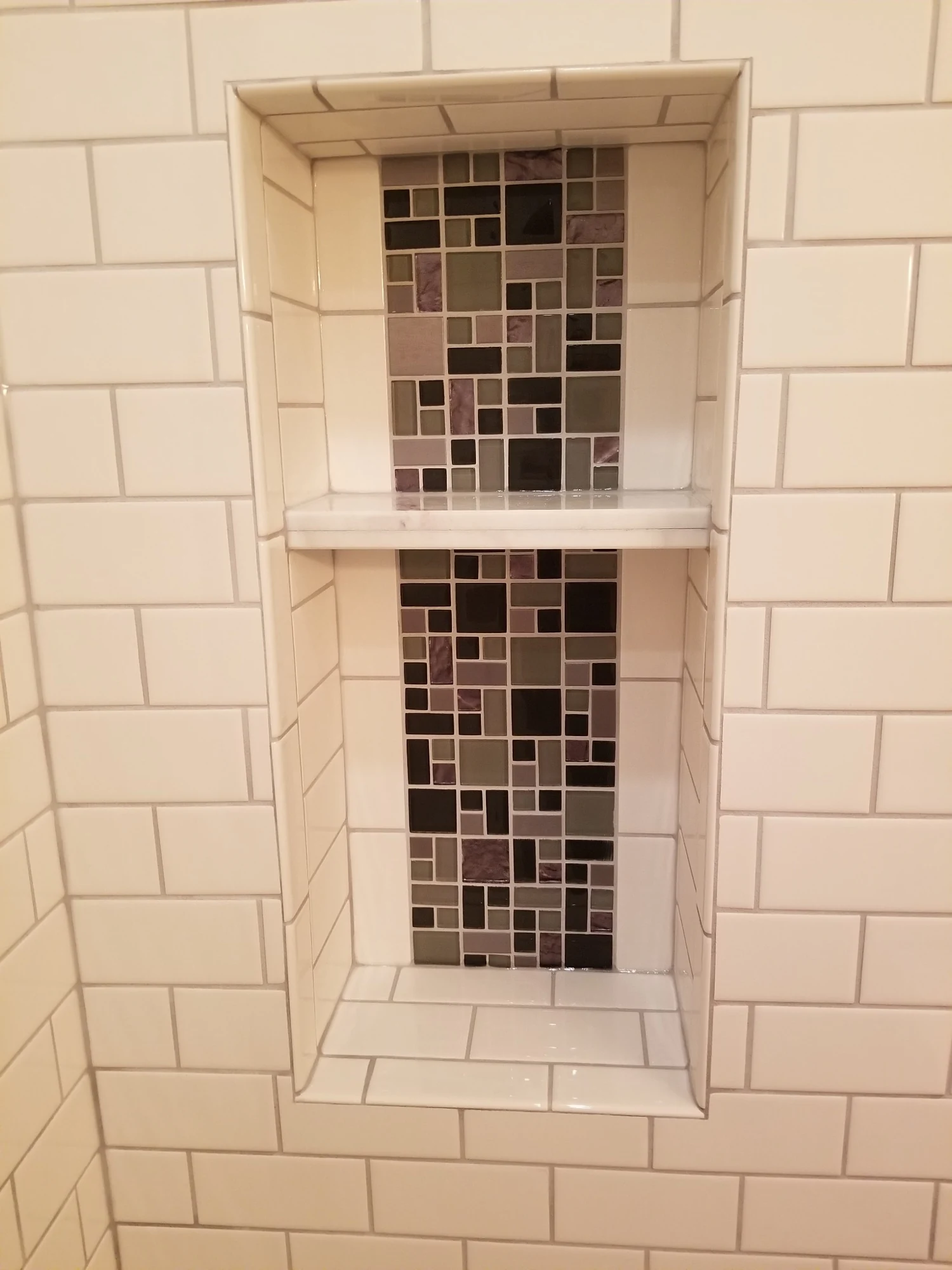 Custom recessed shower niche with mosaic tile
