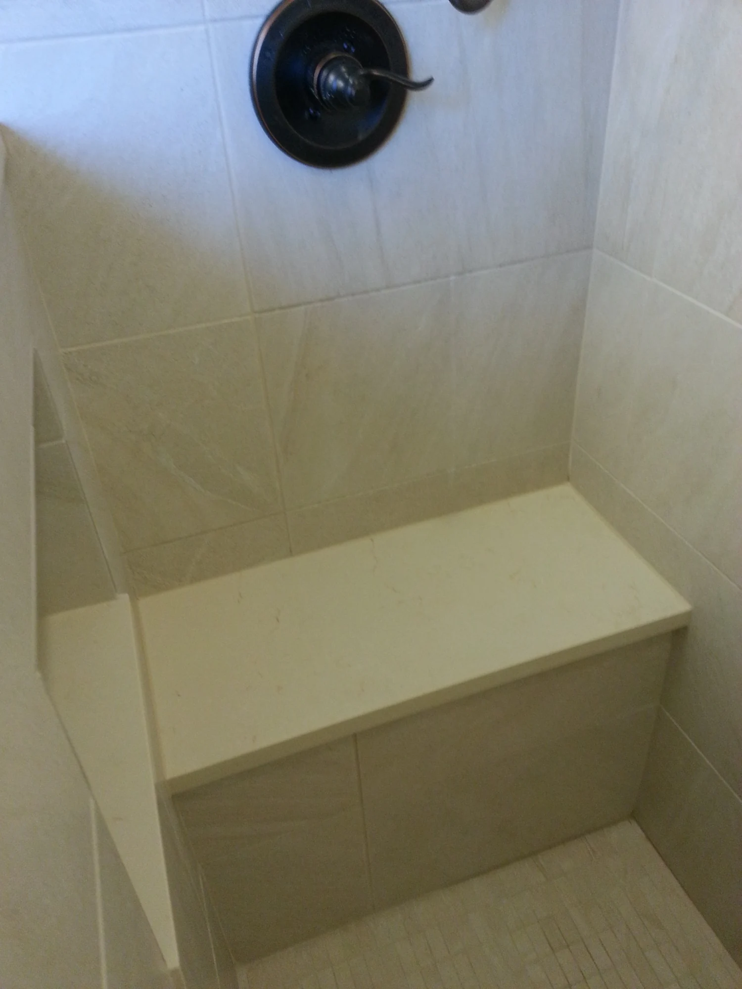 Tiled shower bench and dark shower controls