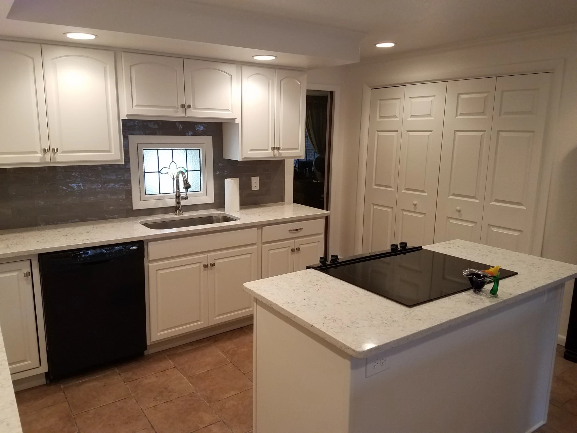 White kitchen remodel with island cooktop, quartz countertops and updated cabinetry