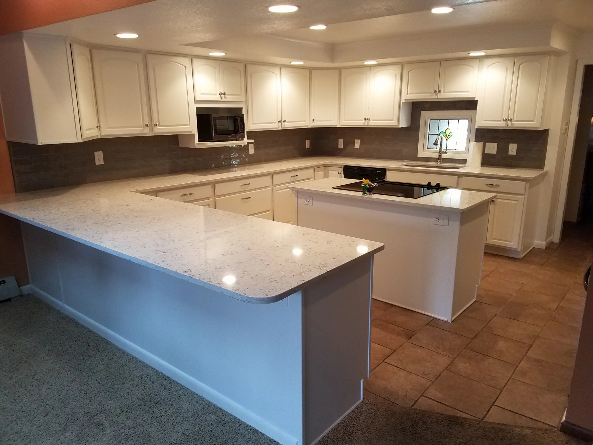 Bright white kitchen remodel with quartz counters, island and recessed lighting