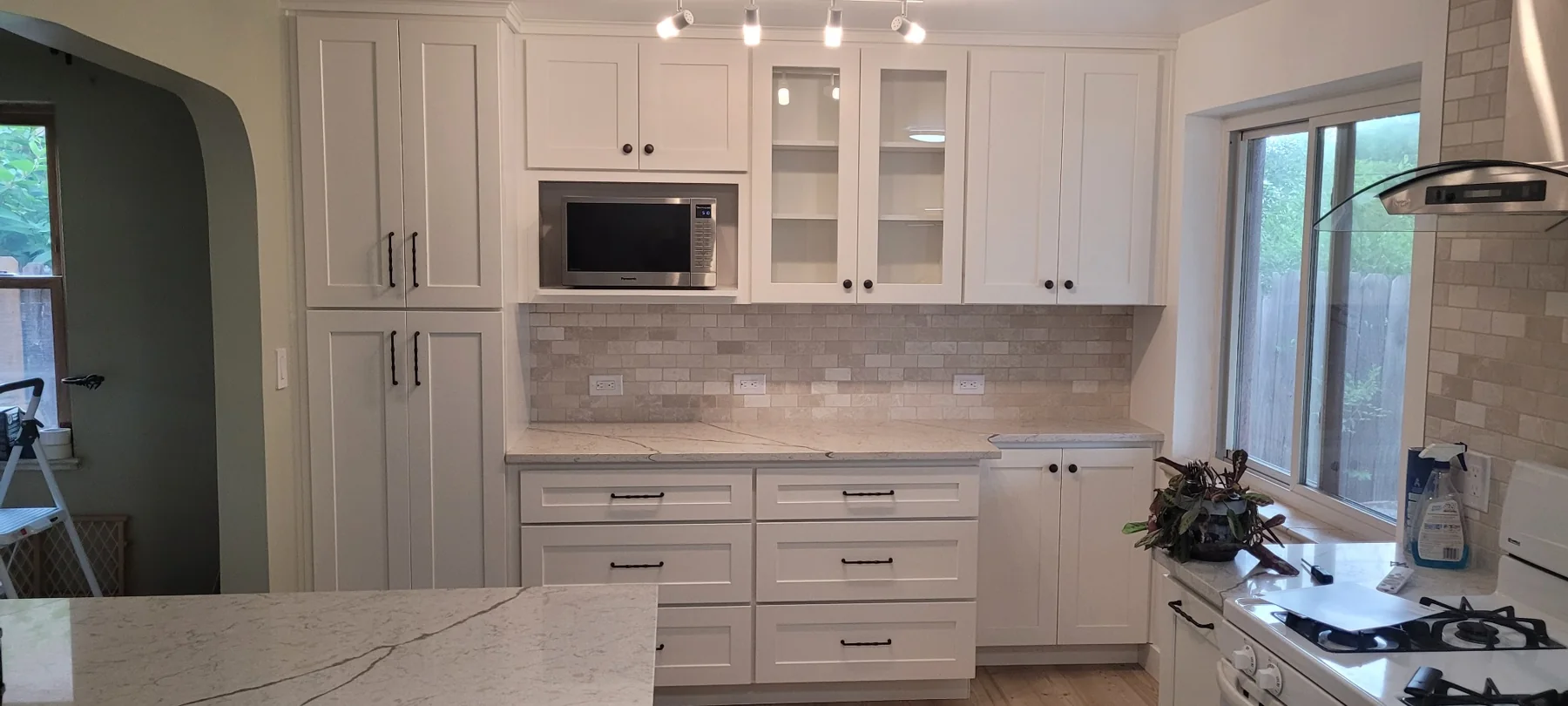 Bright remodeled kitchen with white cabinetry and stone countertops